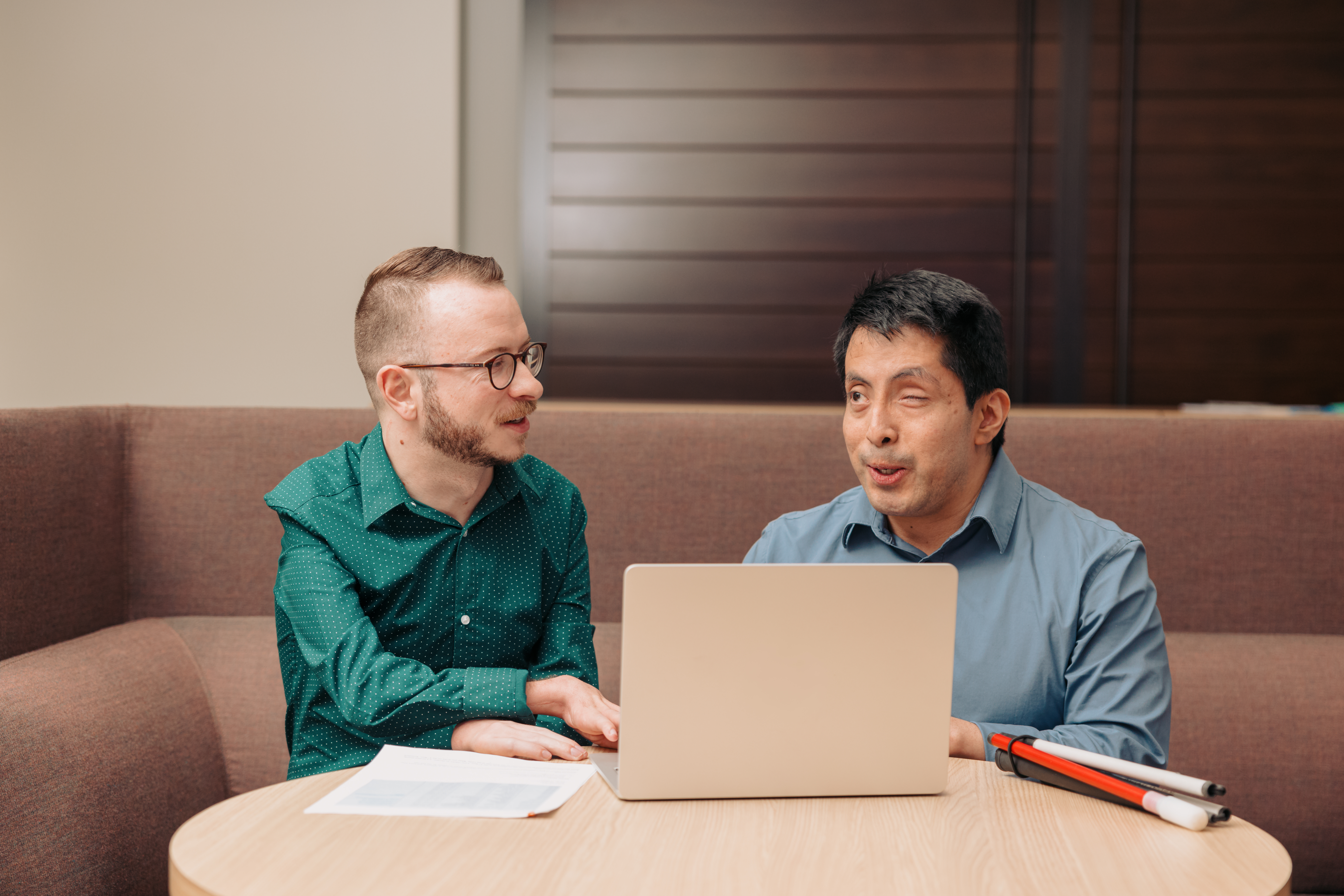 Two colleagues working on a computer together, representing the BuddyHub community platform.
